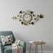 Decorative wall clock with floral and butterfly design on a gray wall above a blue armchair.