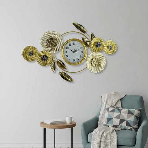 Decorative wall clock with floral designs on a wall above a blue armchair.