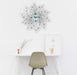 Decorative wall clock on a white wall above a desk with a chair.