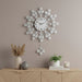 Decorative wall clock with floral design on a wall above a wooden cabinet with decor items.