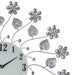 Decorative wall clock with floral and leaf designs on a white background
