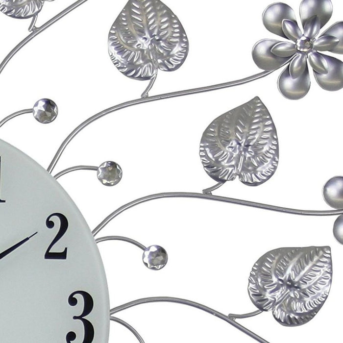 Decorative wall clock with floral and leaf designs on a white background
