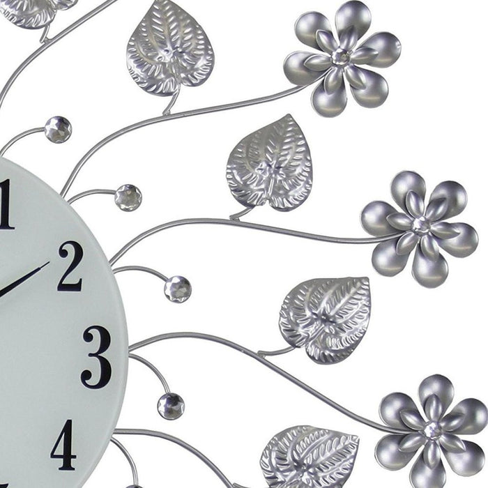 Decorative wall clock with floral and leaf designs on a white background