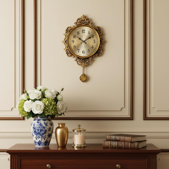 Decorative clock on a wall with a vase, books, and candle on a wooden table below.