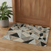 Geometric patterned rug on a wooden floor with a plant and wooden door in the background