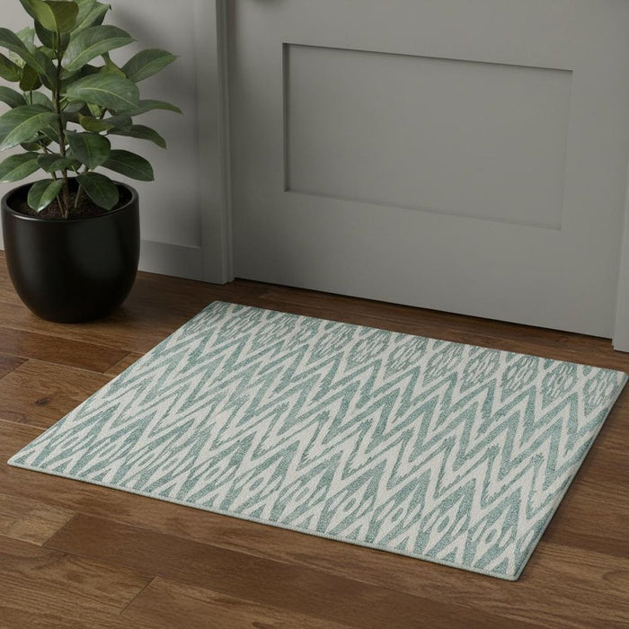 Patterned rug on a wooden floor with a plant and door in the background