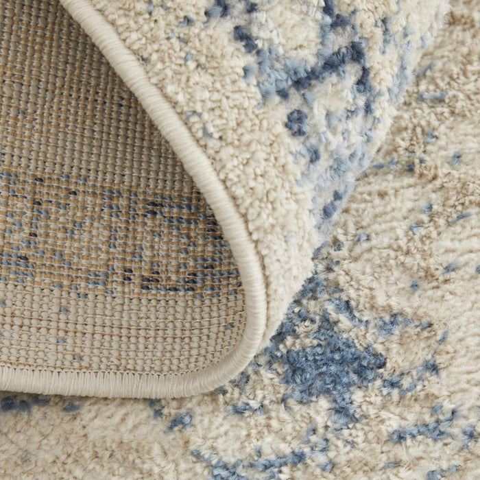 Close-up of a textured beige and blue area rug corner.