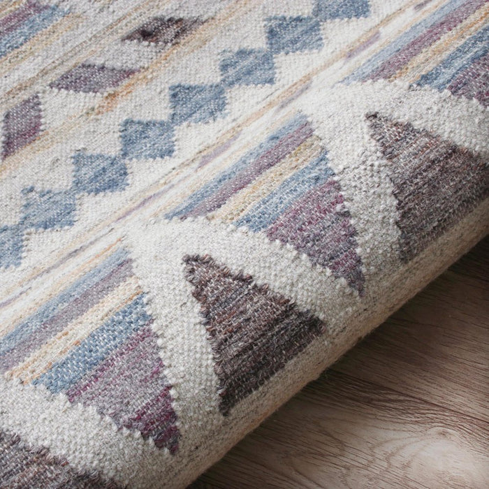 Close-up of a textured rug with geometric pattern on a wooden floor