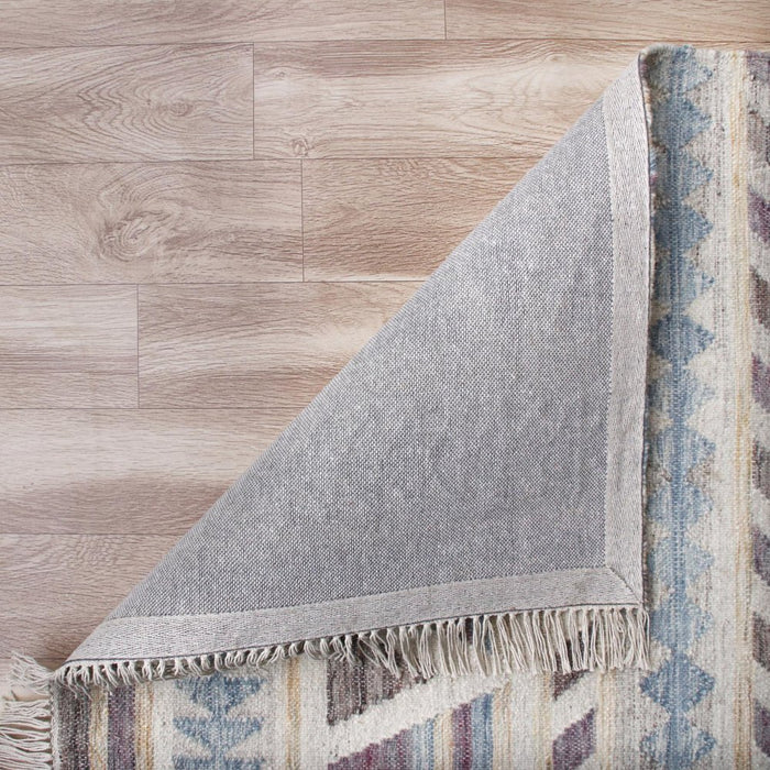 Corner of a patterned rug on a wooden floor