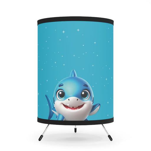 A cute Cartoon Shark Decorative Table Lamp on a tripod with a starry blue background.