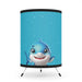 A cute Cartoon Shark Decorative Table Lamp on a tripod with a starry blue background.