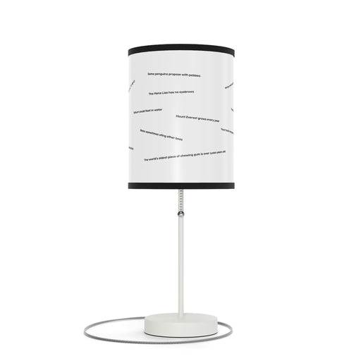 The "Random Fact" lamp features a text-patterned white cylindrical shade and a slim metallic base.