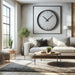 Modern living room with minimalist design featuring a stylish black wall clock above a gray sofa, wooden coffee table, large window, and tasteful decor including plants and contemporary art pieces.